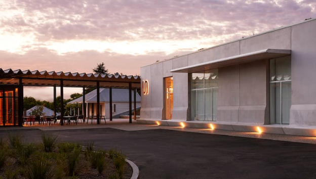 Exterior view of Bundanon Museum as the sun sets with pink and purple hues as the entrance lights come on