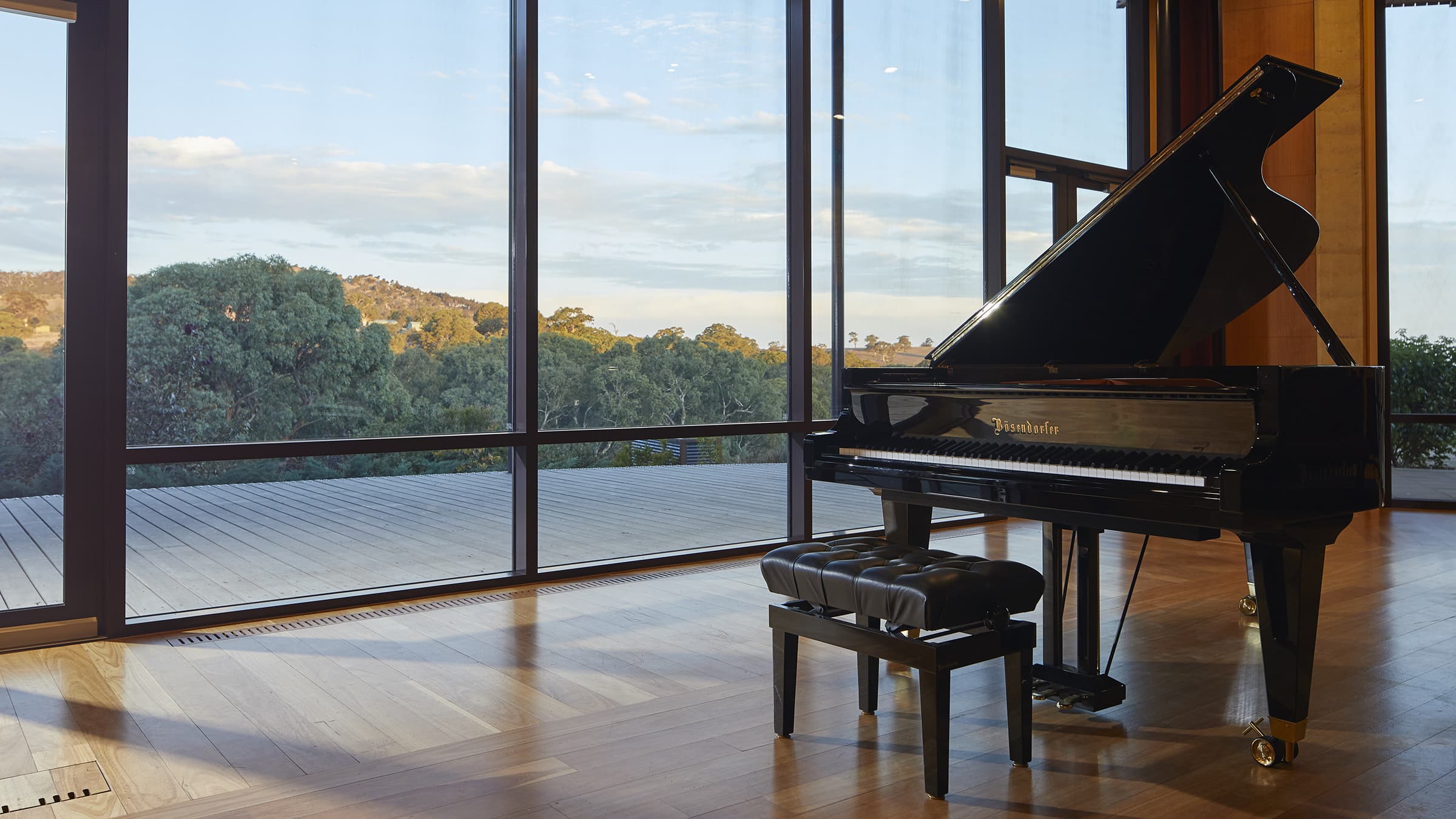 Inside view of a performance room in the Ukaria Cultural Centre looking out through glass doors to the surrounding green mountains
