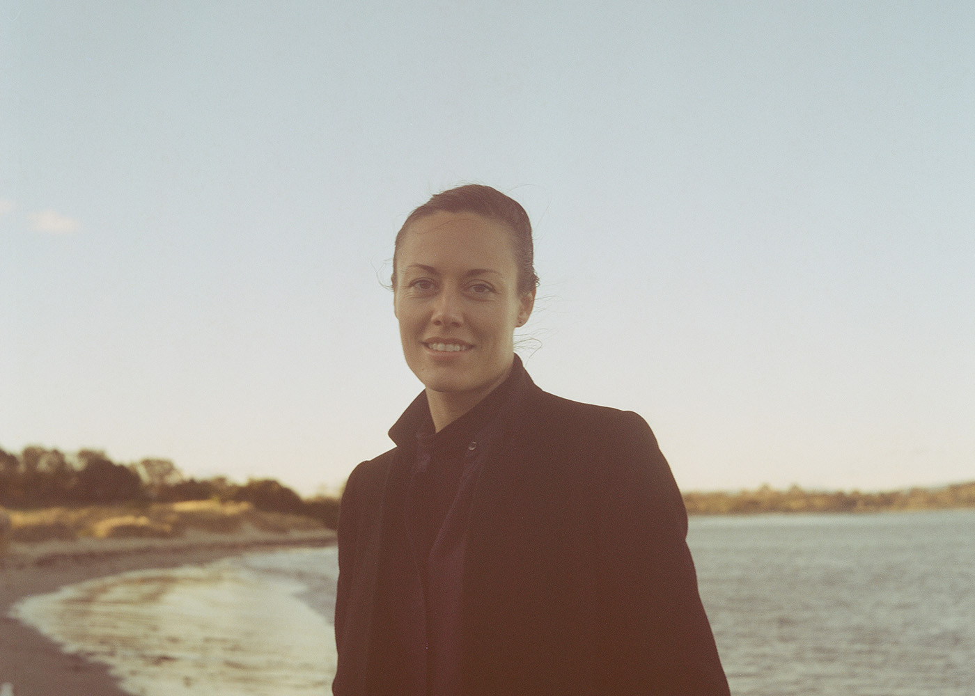 Lisa Illean on a Tasmanian beach looking to camera on a nice blue sky day